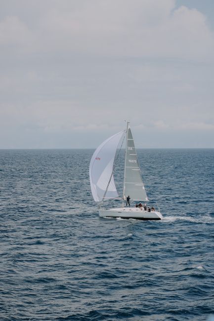 A sailboat glides smoothly over the open sea under a cloudy sky, capturing a serene maritime scene.