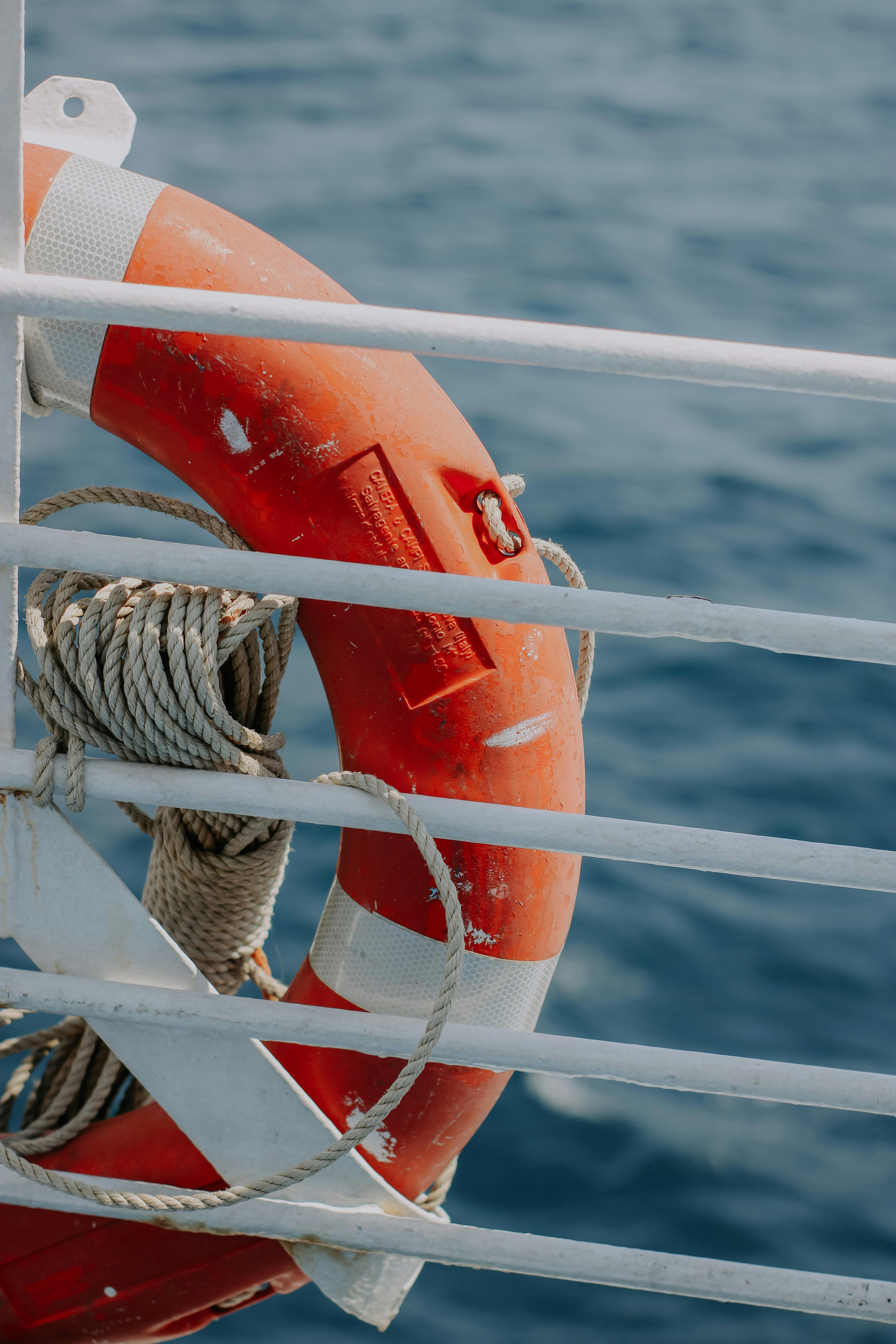 Detailed view of a lifebuoy with ropes on a boat against the blue sea background.