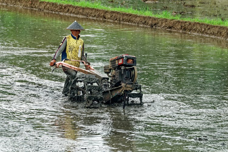 Man Pushing Wheeled Machine Into Body Of Water