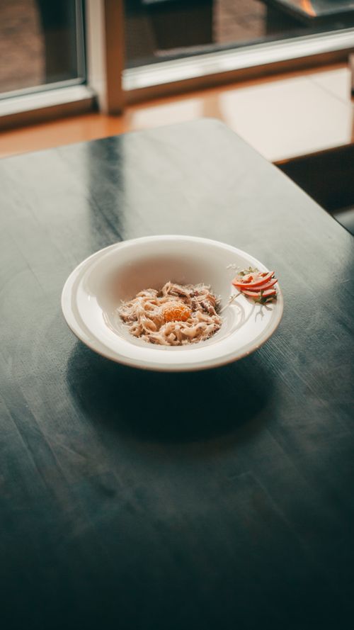 Free A beautifully plated gourmet pasta dish served in a modern restaurant setting with natural light. Stock Photo