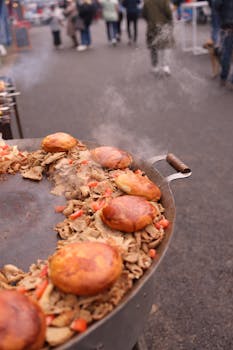 Freshly grilled buns and vegetables at a bustling street food market, with a visible crowd.