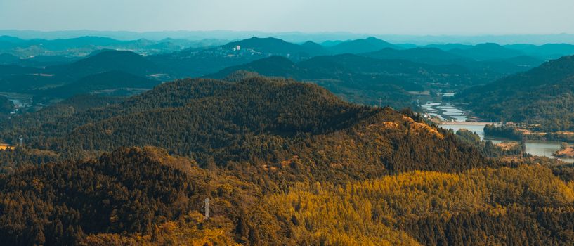 Stunning aerial view of a forest and hills showcasing vibrant fall colors and natural beauty.