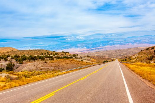 Beautiful sunlit countryside road stretching into the horizon, surrounded by serene rural landscapes.