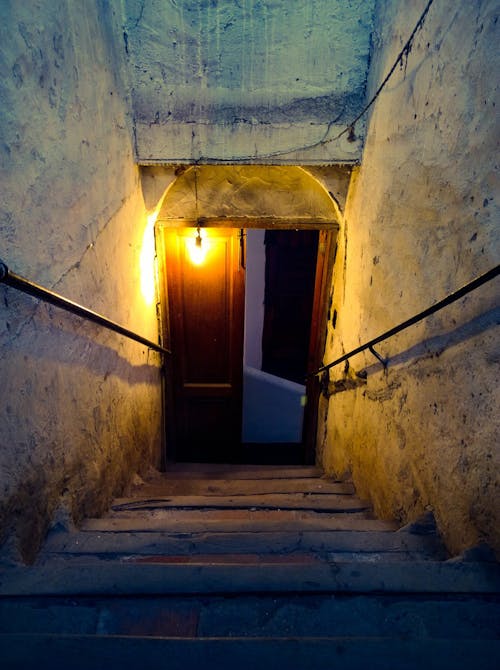 光のあるコンクリートの階段の近くの茶色の木製ドア