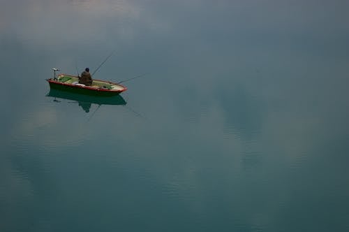 High Angle Shot of a Fisherman in a Boat on a Calm Water Surface