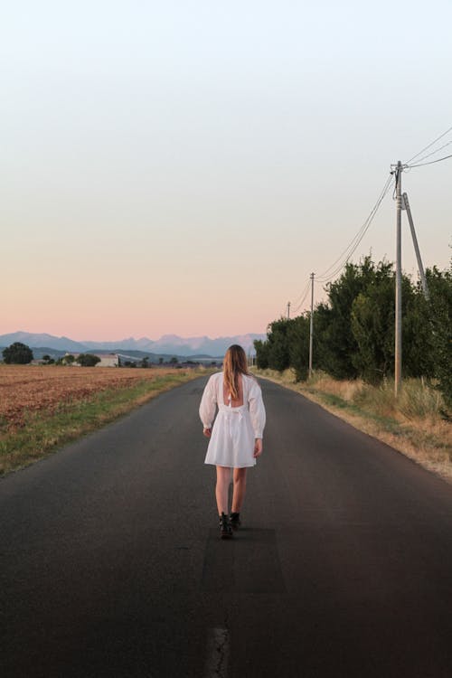 Blonde Woman in White Dress on Road in Countryside