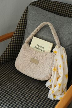 Chic plush handbag and book elegantly placed on a patterned chair.