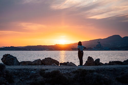 Woman Standing on Sea Shore at Sunset