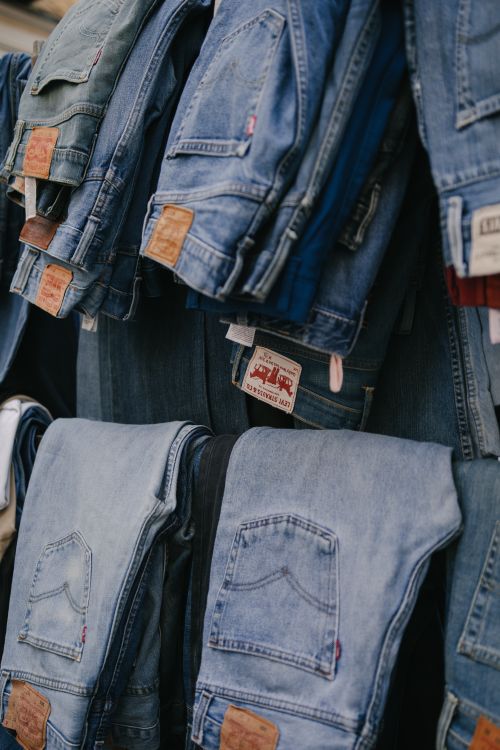 Free Folded and hanging jeans in a clothing store in Madrid, showcasing fashion variety. Stock Photo