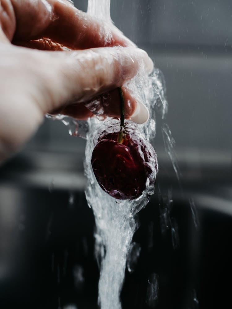 Hand Of A Woman Washing A Single Cherry