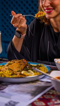 Woman eating a flavorful rice dish with vegetables, garnished beautifully, and enjoying the taste.