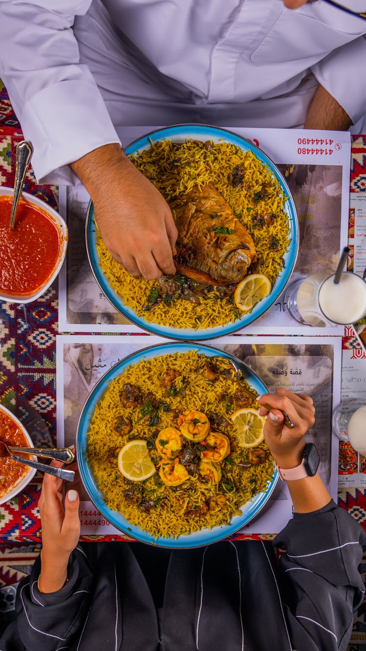 Top View Of People Sitting And Eating A Dish With Rice 