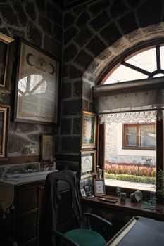 A cozy home office with vintage decor, stone walls, and natural light through an arched window.