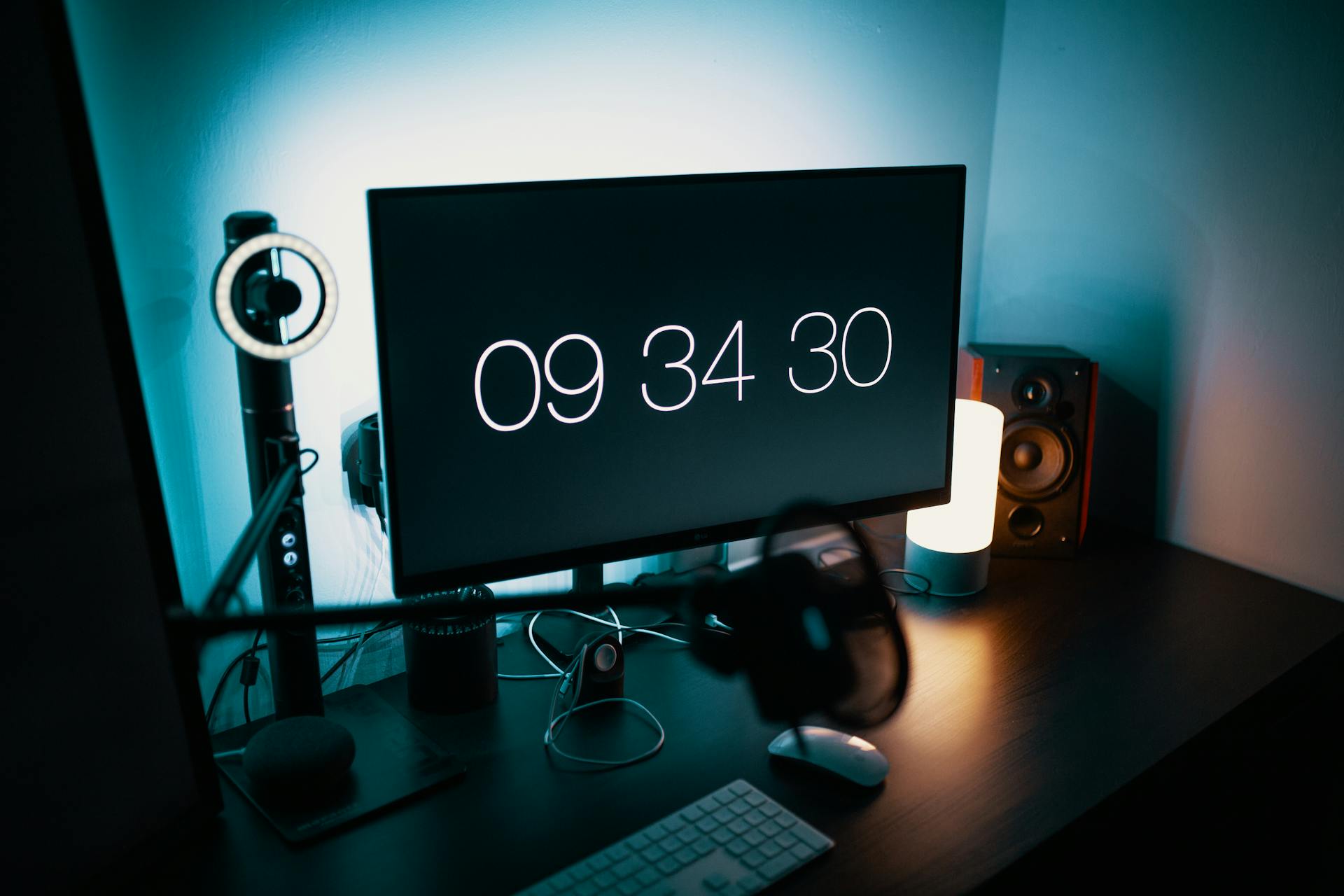 A sleek desk setup featuring a large monitor with a digital clock and ambient lighting.