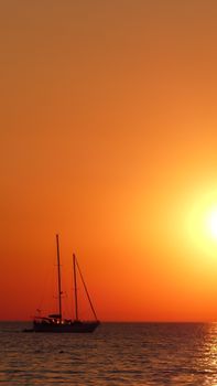 A serene sailboat silhouetted against a vibrant golden sea sunset, evoking tranquility.