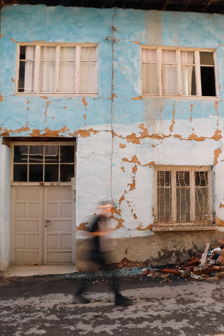 Blurred Man Walking Near Damaged Building Wall In Town In Turkey