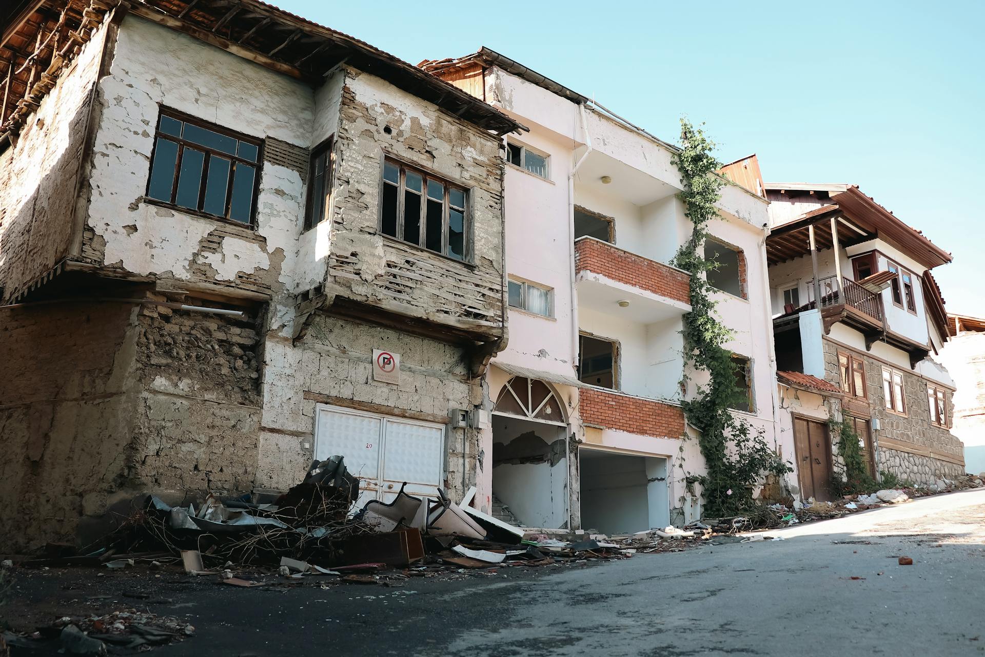 A street view of abandoned and decaying buildings in an urban area, showing signs of damage and neglect.