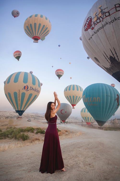 Female Model Posing in Front of Rising Hot Air Balloons