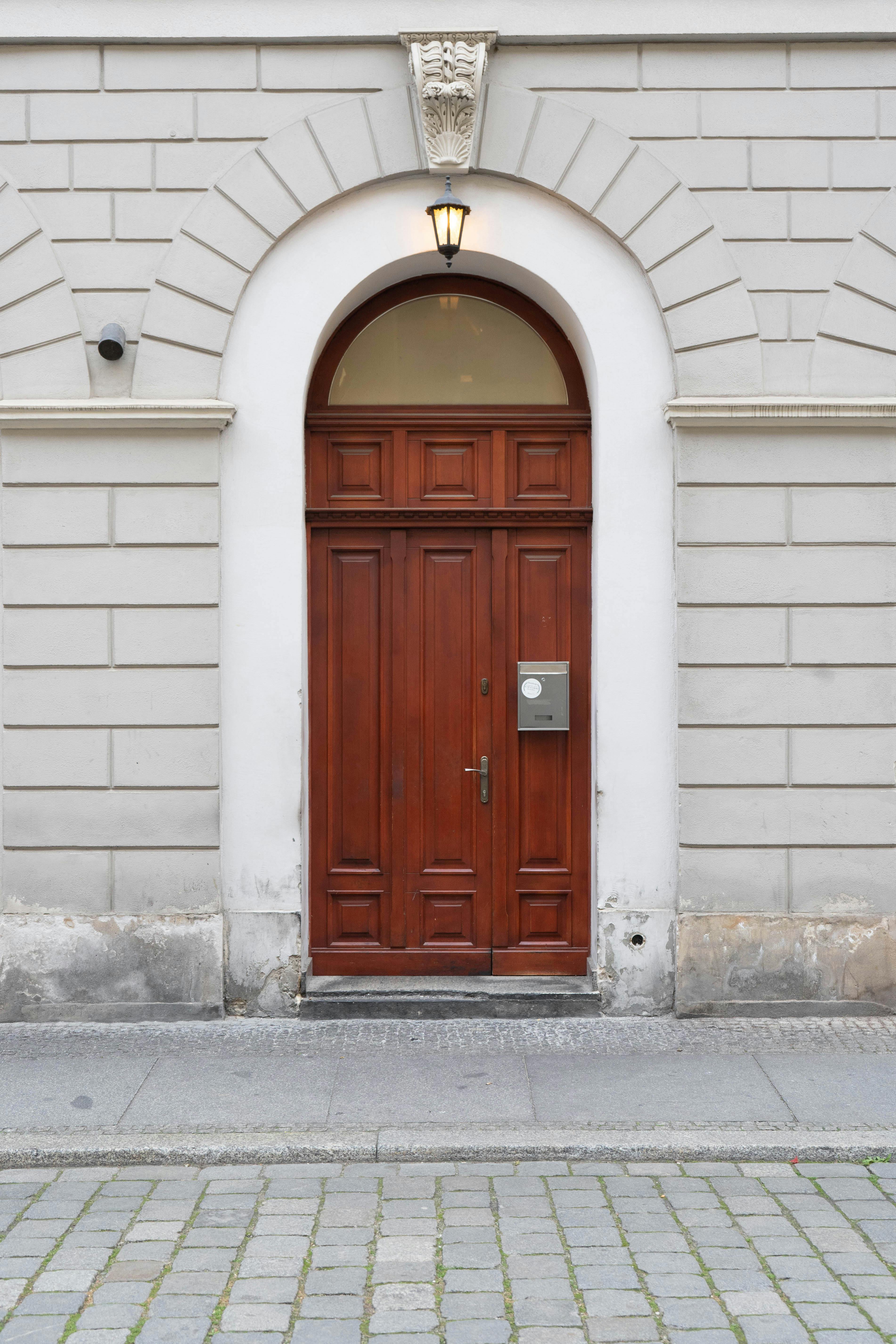 A classic wooden door set in a white stone wall on a city street in Wroclaw, Poland.