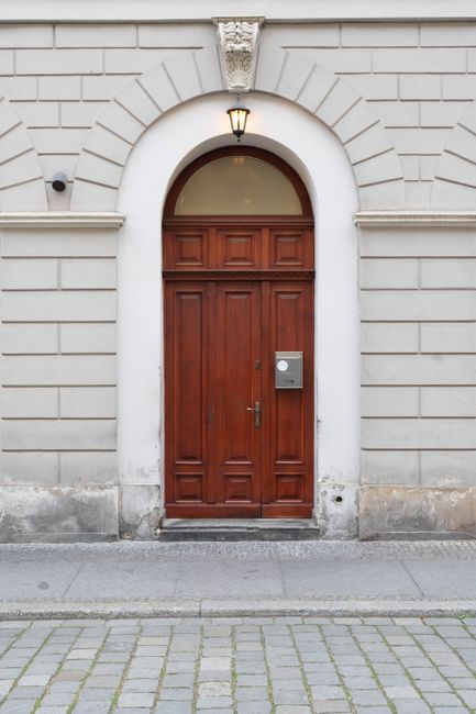 A classic wooden door set in a white stone wall on a city street in Wroclaw, Poland.