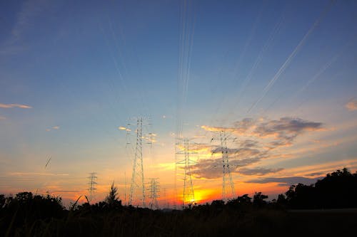 Three Black Metal Electricity Posts during Golden Hour