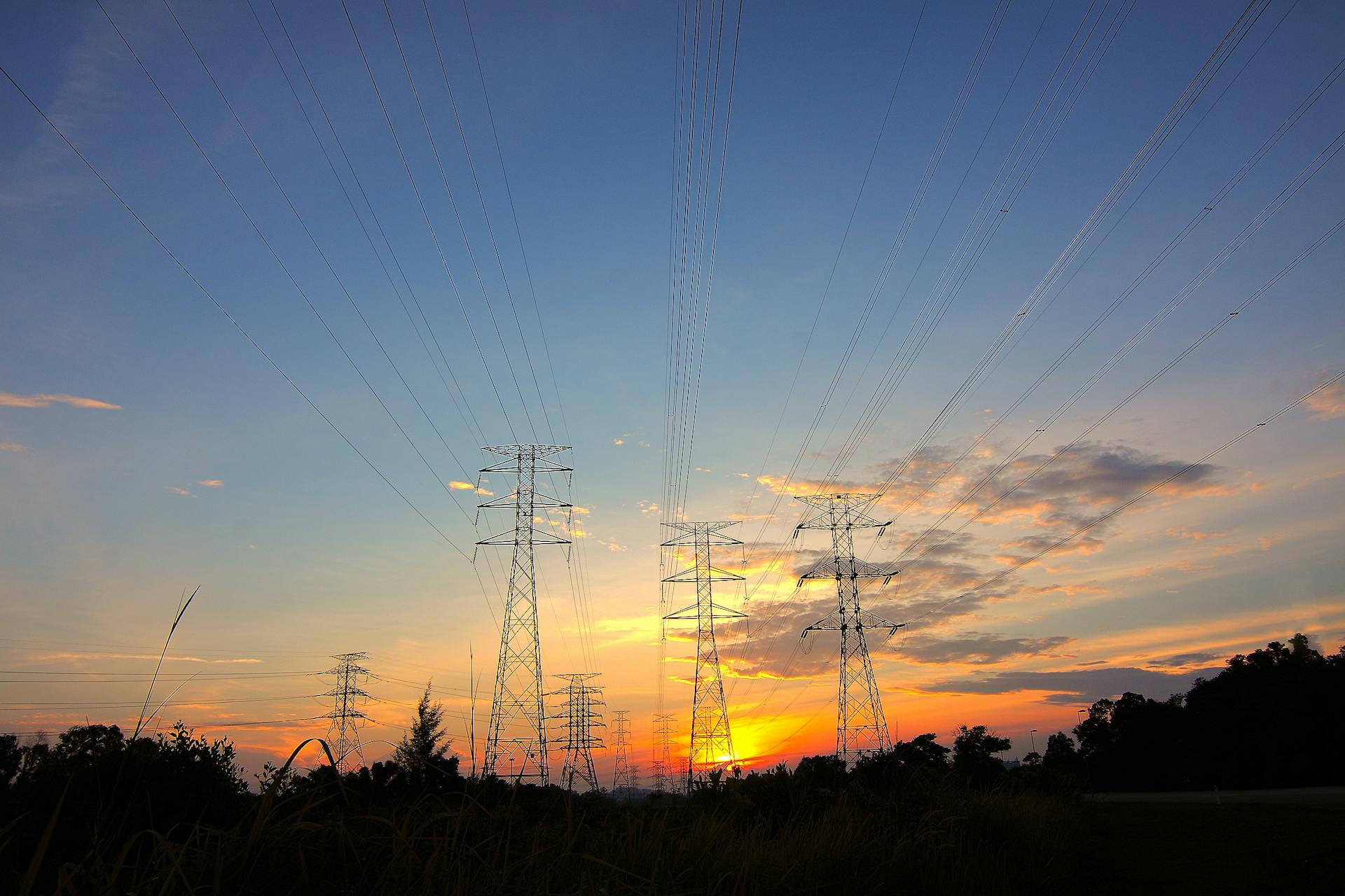 Three Black Metal Electricity Posts during Golden Hour