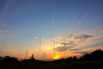 Three Black Metal Electricity Posts during Golden Hour