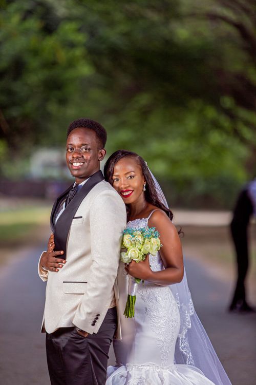 Free Smiling newlywed couple poses outdoors in elegant wedding attire. Stock Photo