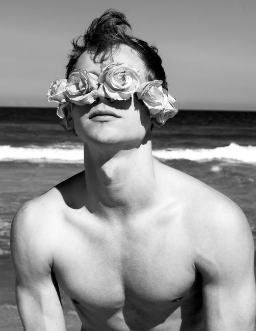 Creative portrait of a man with roses at the beach in Rio, captured in black and white.