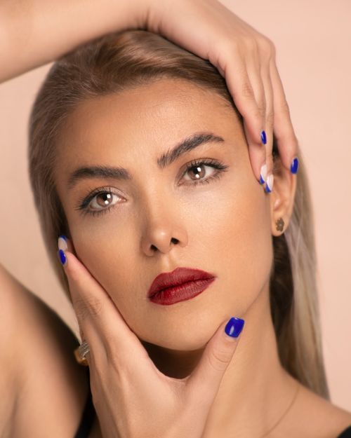 Free Close-up portrait of a woman with red lipstick and blue nails, striking a pose. Stock Photo