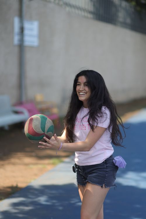 Free A smiling woman plays with a volleyball in a casual outdoor setting. Stock Photo