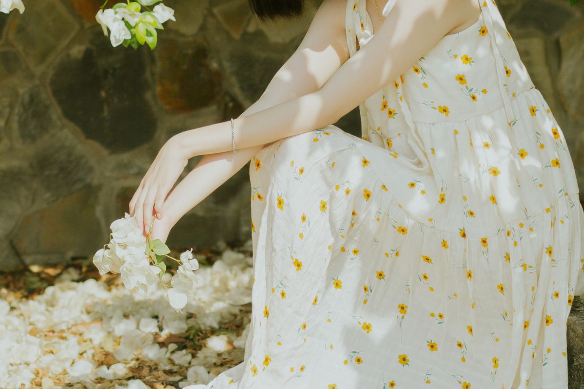 A woman holding flowers in a delicate floral dress — styling the floral with a light hand