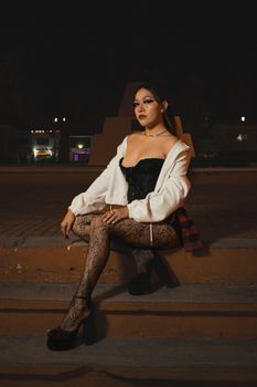 Stylish woman poses confidently in trendy night attire on outdoor steps.
