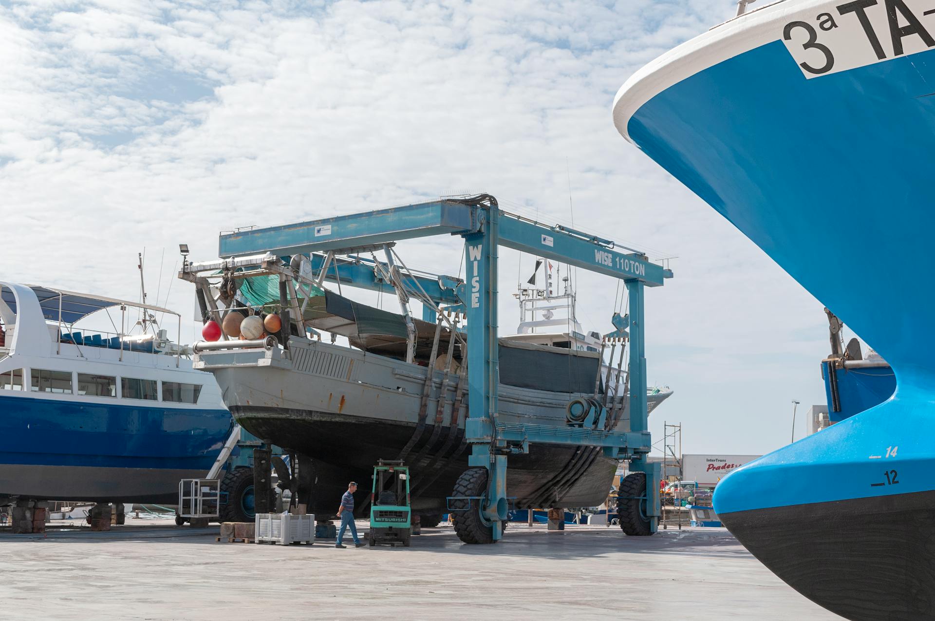 Industrial ships in dry dock with large dock lift machinery at a port. Calm daytime scene.