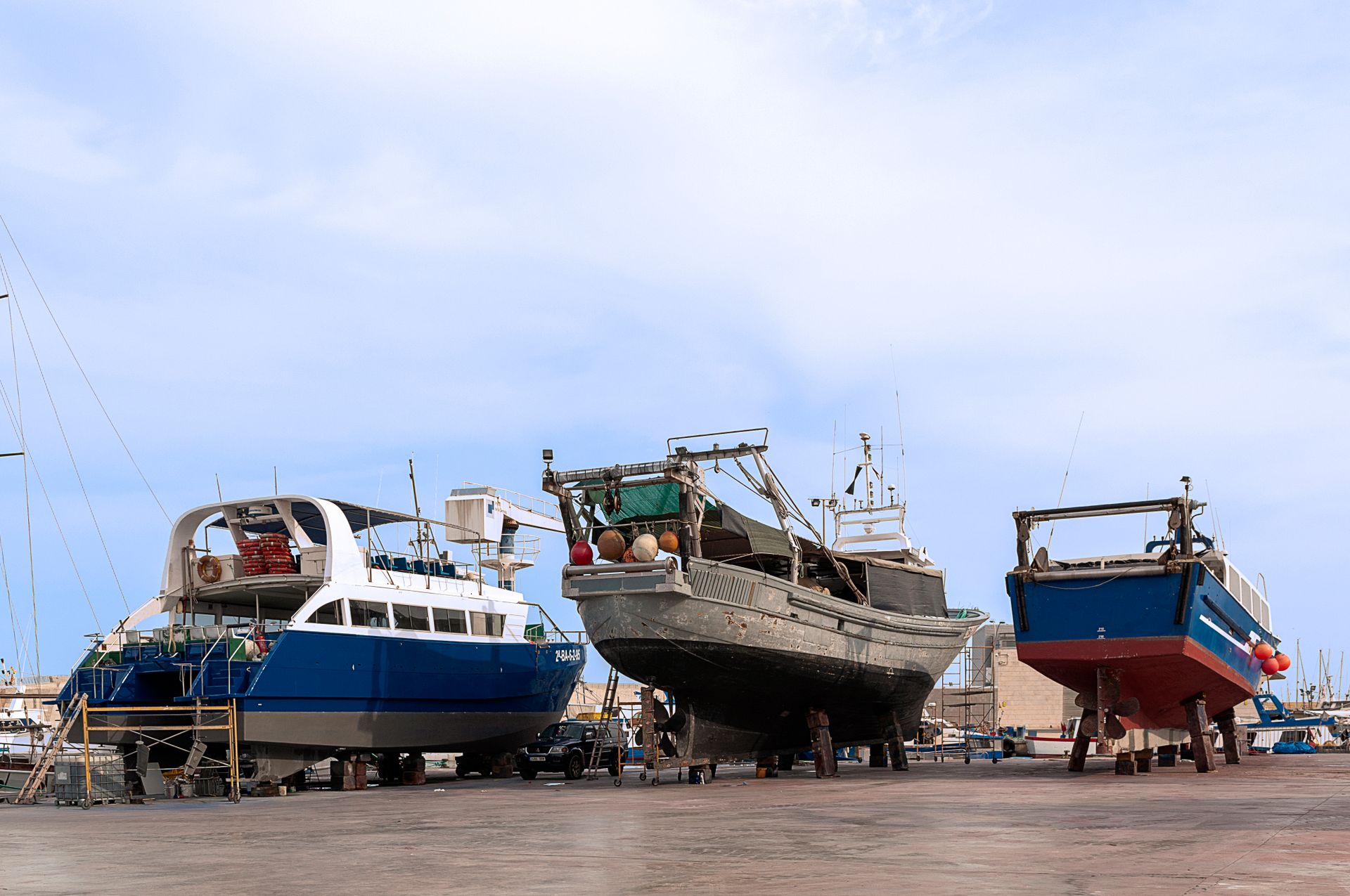 Multiple vessels in a dry dock for maintenance against a clear sky backdrop.