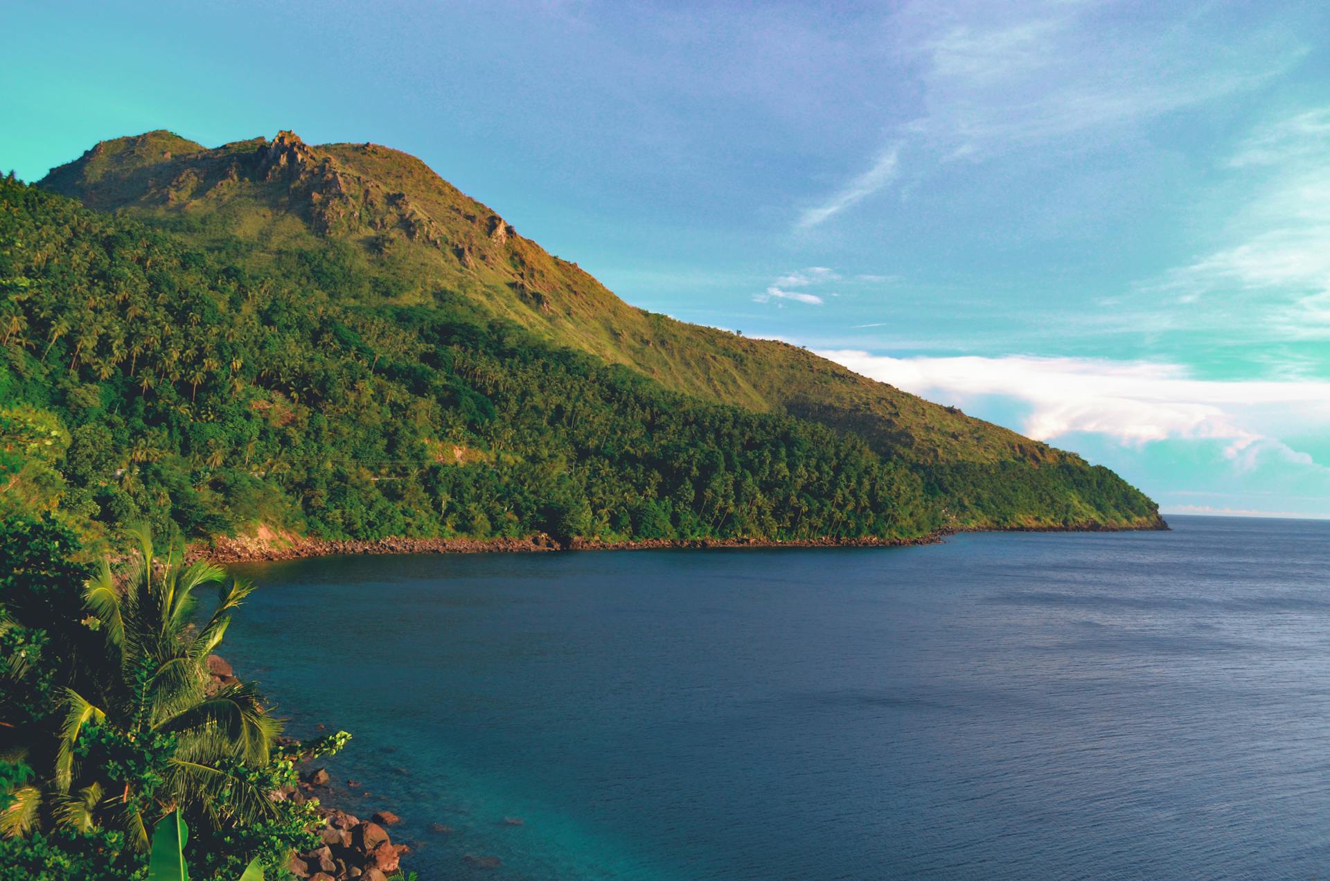 Beautiful tropical coast with lush mountains and clear ocean waters under a bright sky.