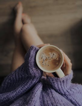 Woman in a purple sweater cozying up with a warm cup of coffee. Perfect for a quiet morning moment.