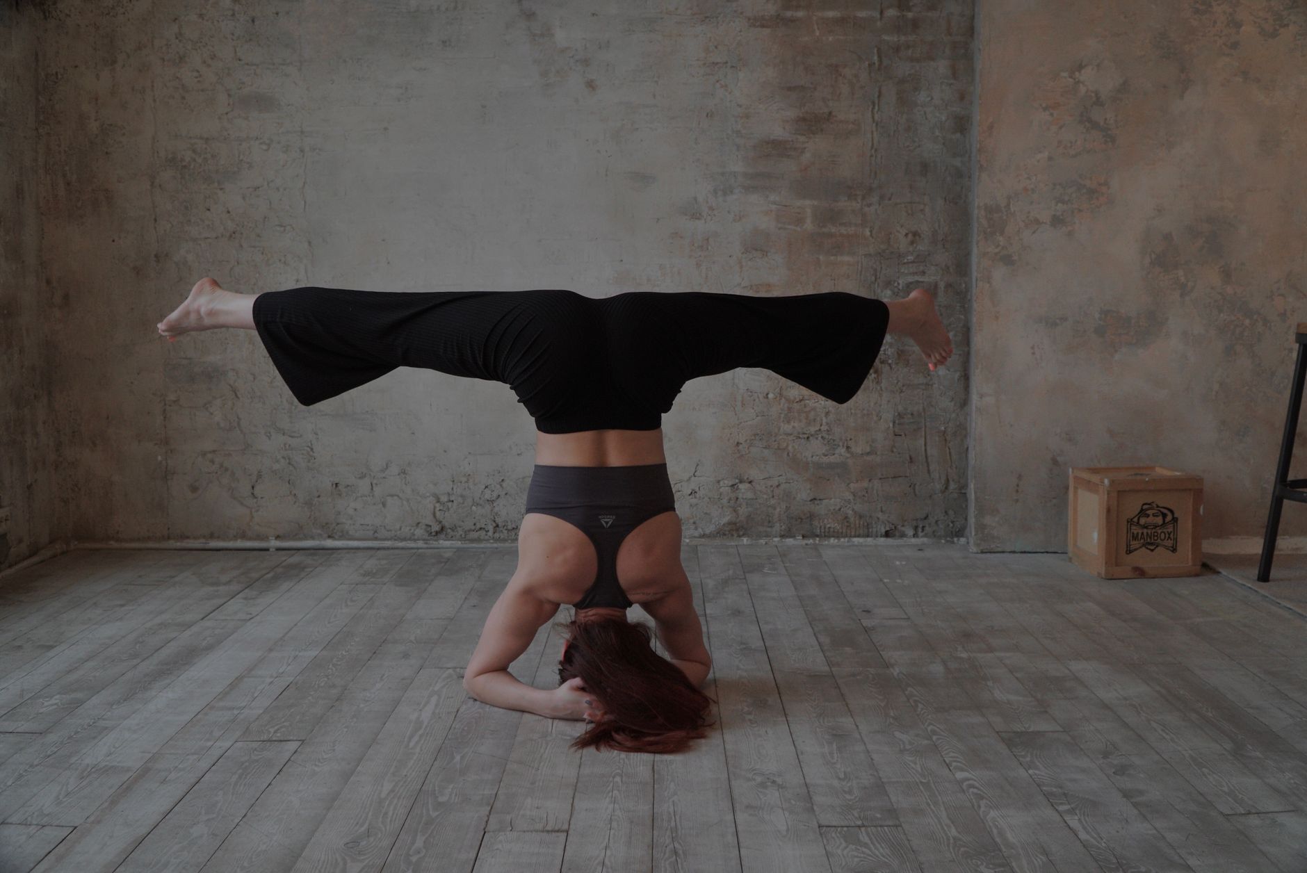 A woman in a yoga headstand pose indoors, showcasing strength and balance in a studio setting.