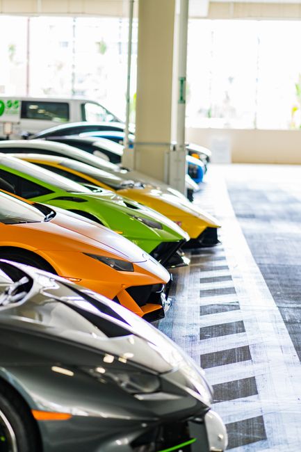 A lineup of colorful luxury sports cars parked indoors, showcasing sleek designs and vibrant colors.