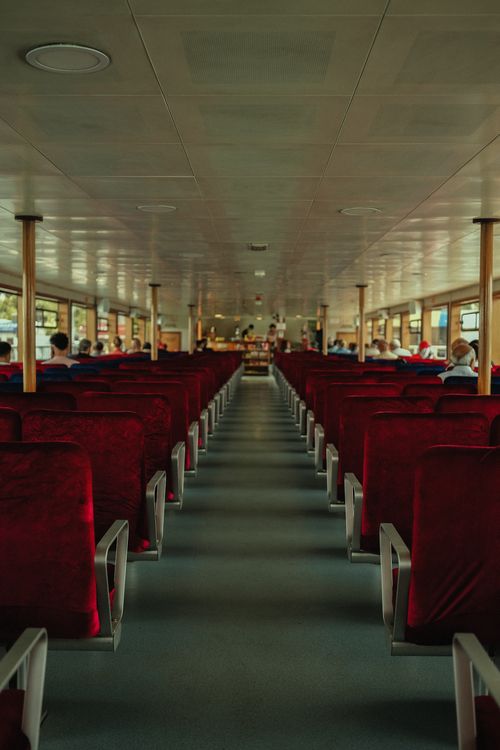 Free Symmetrical view inside a passenger ferry with empty red seats and peaceful atmosphere. Stock Photo