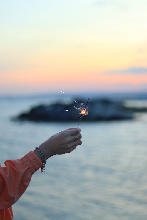 Woman Hand Holding Sparkler at Sunset