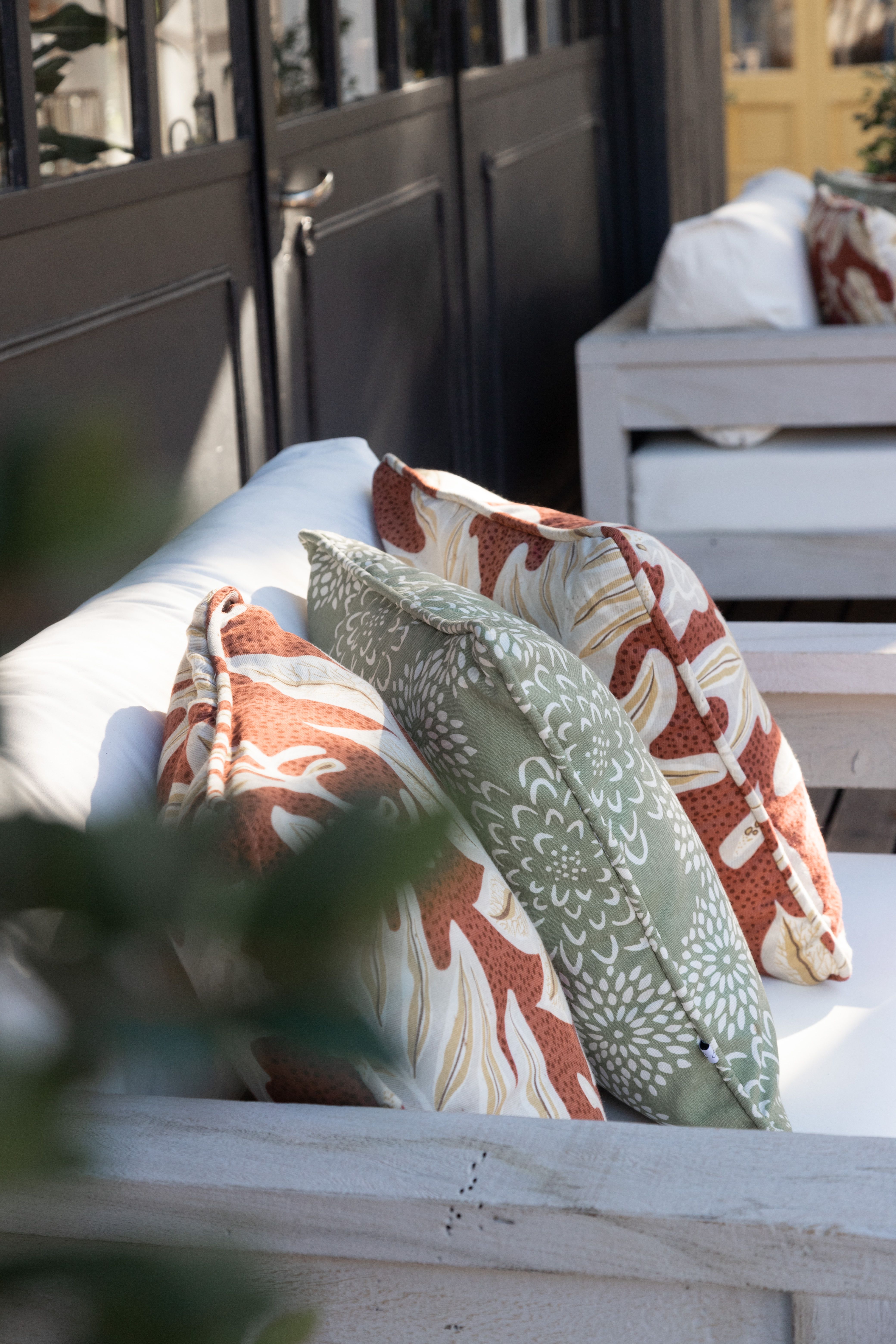 Outdoor bench styled with patterned weatherproof cushions on a patio