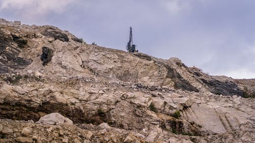 Free Rocky quarry site with visible erosion and industrial machinery against an overcast sky. Stock Photo
