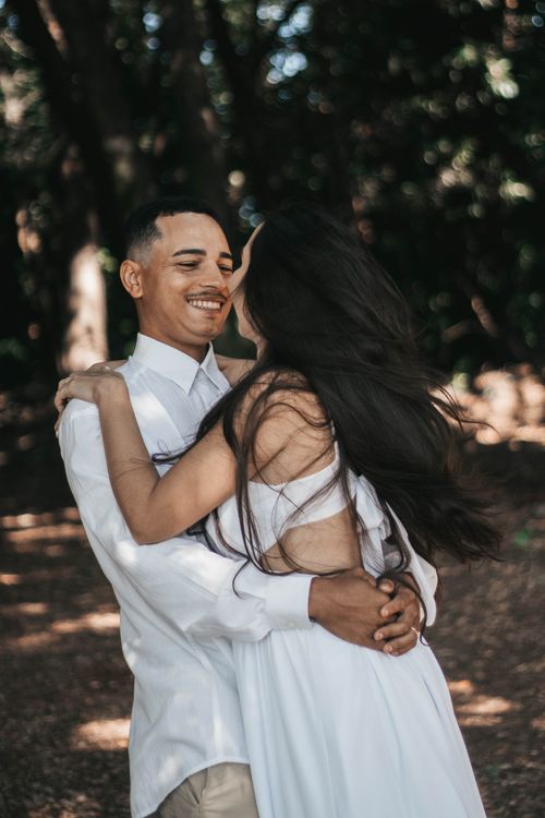 Free A joyful couple embracing in a sunlit forest setting, capturing love and romance. Stock Photo