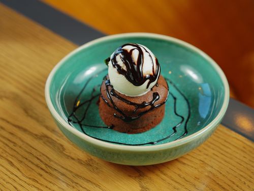 Free Delicious chocolate lava cake topped with vanilla ice cream and chocolate sauce in a green bowl. Stock Photo