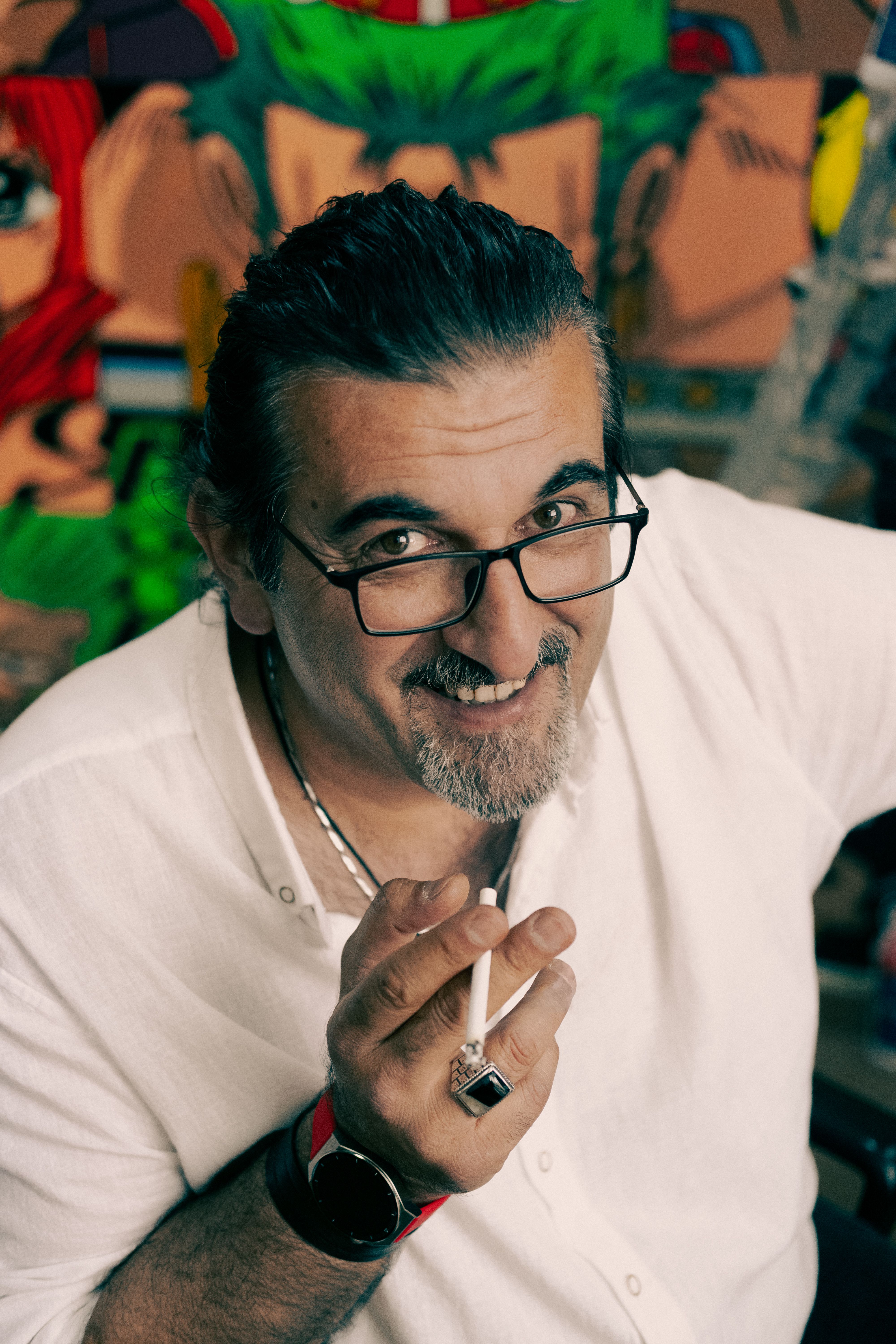 Cheerful man with glasses and black hair holding a cigarette in Ankara, Türkiye.