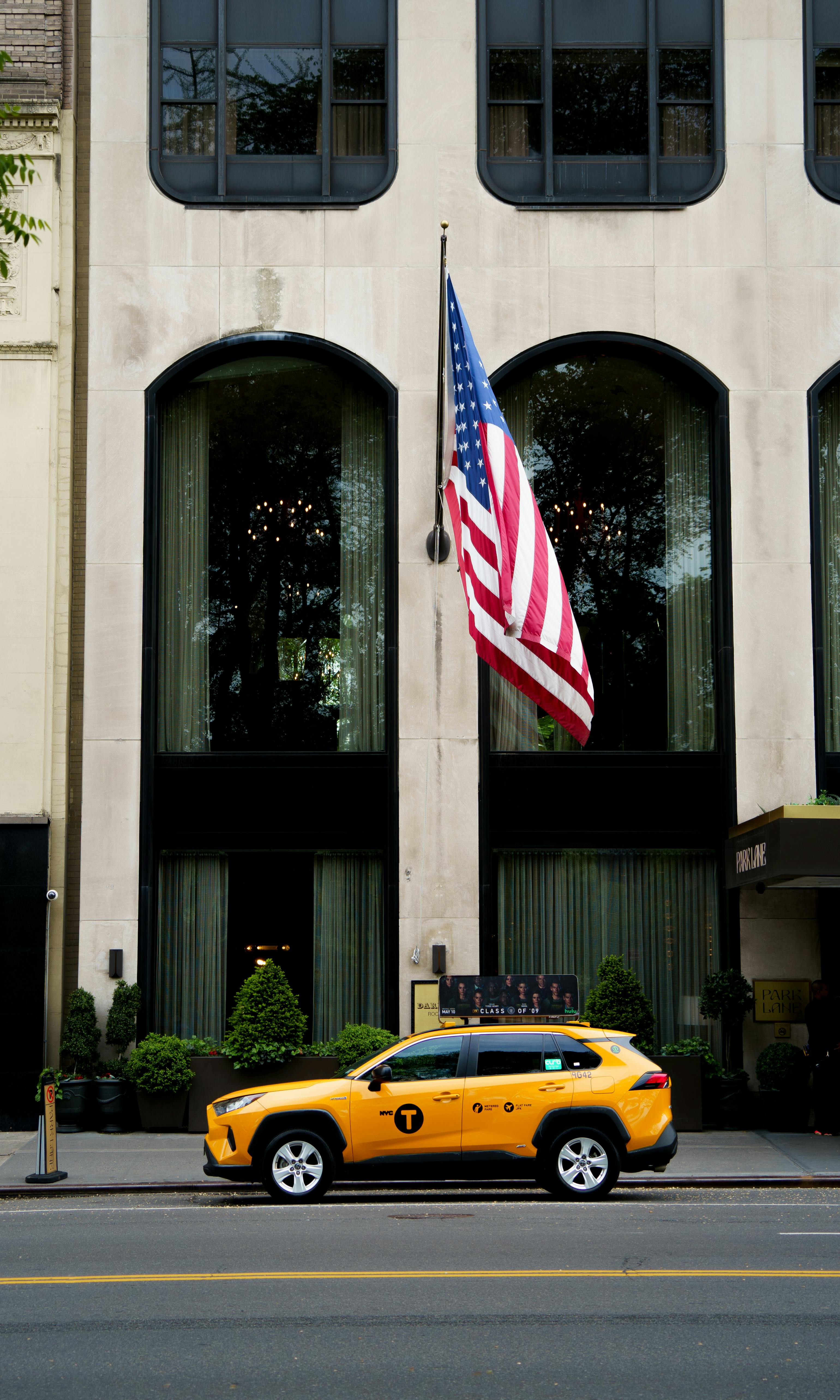 taxi cab on street by american flag on building