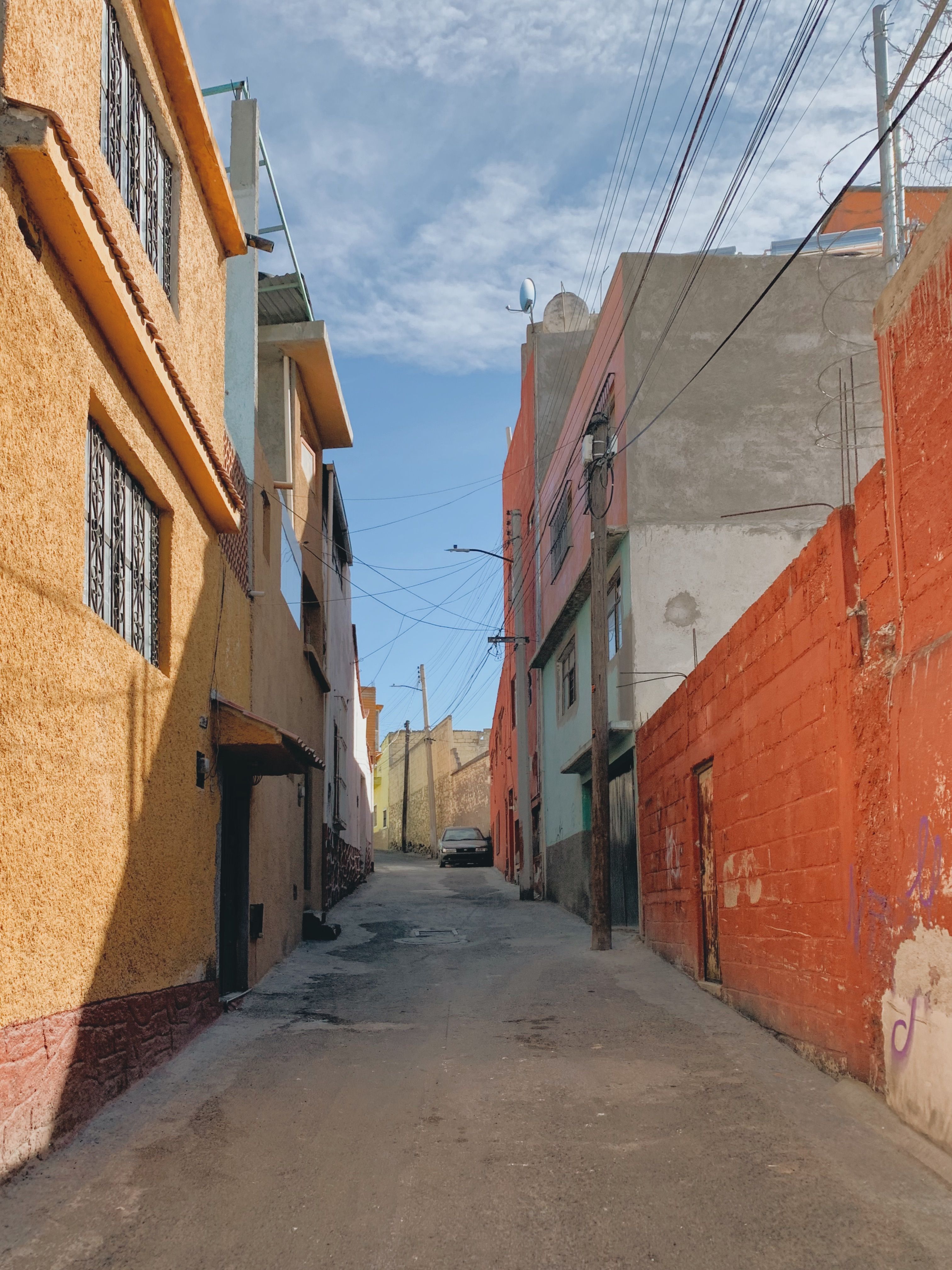 Vibrant narrow street in Pachuca, Mexico, with colorful buildings and clear sky.