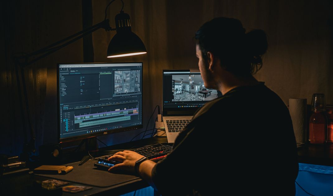 Video editor reviewing and organizing long interview footage in a dimly lit workspace