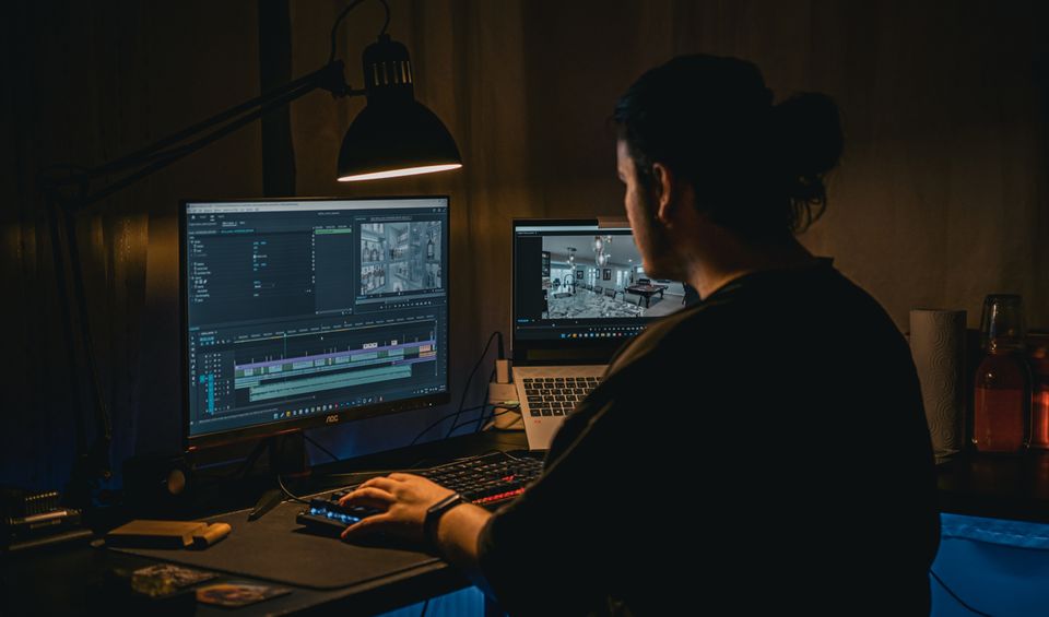 Video editor cutting footage on a computer in a dim studio